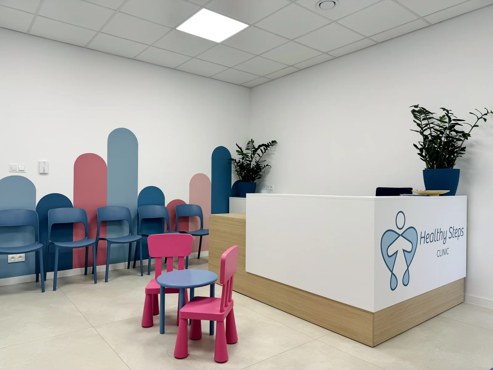 The waiting room at Healthy Steps Clinic in Poznań – reception desk with the clinic logo, seating for patients and a play corner for children